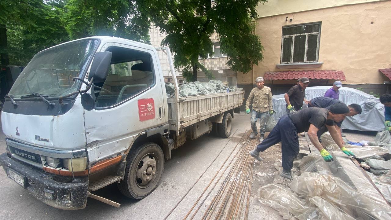 Грузчики загружают арматуру и мешки в наш бортовой грузовик в Алматы